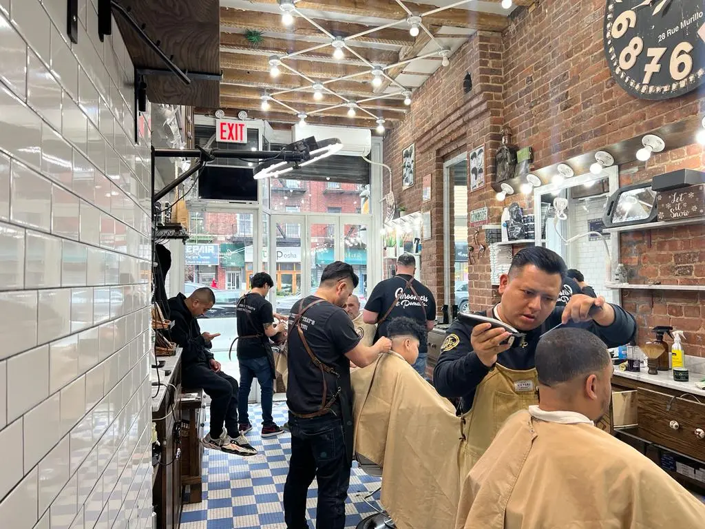 Barbers working inside Groomers & Pomade on Steinway Street in Astoria