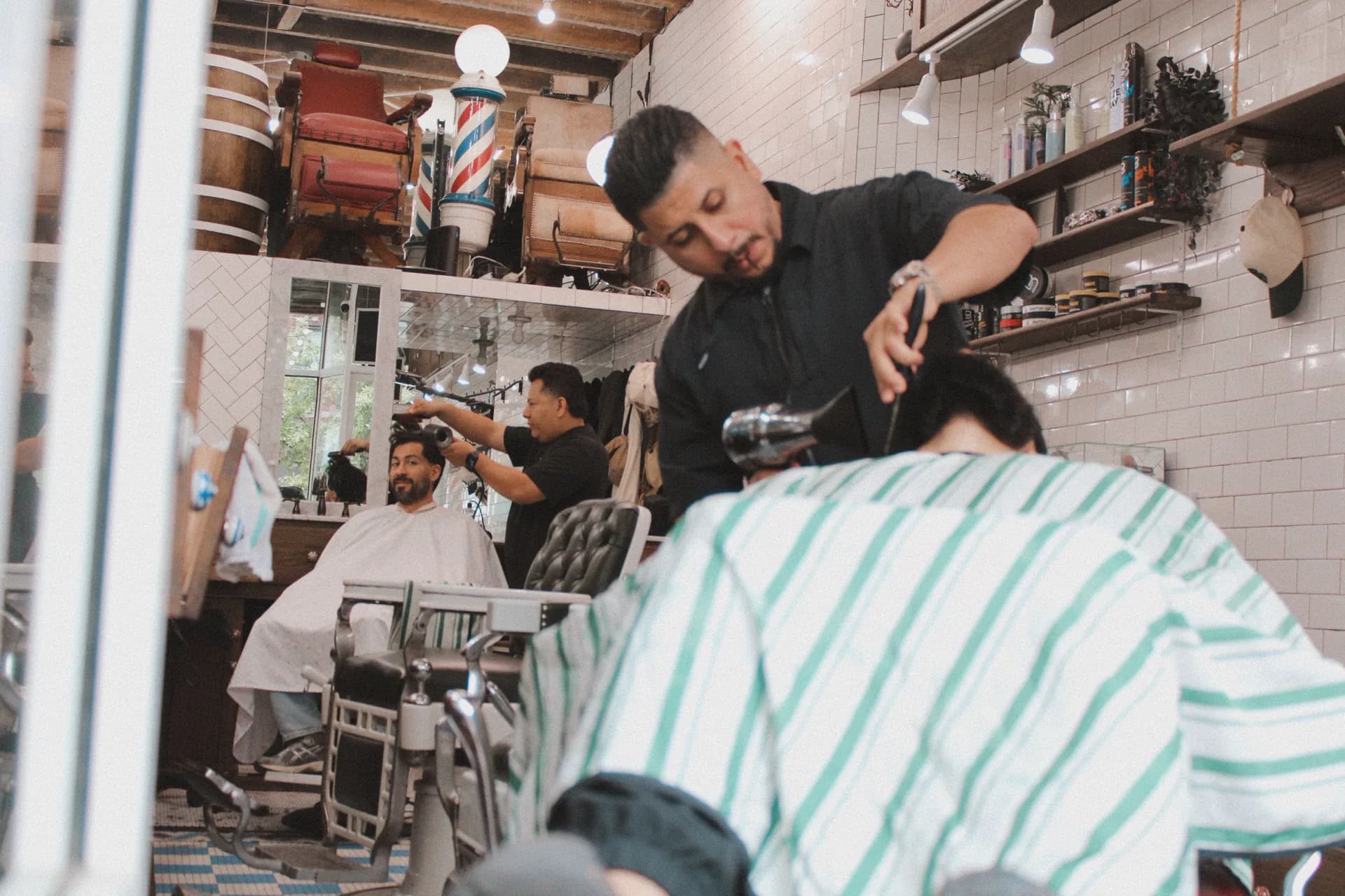 Barbers working with clients inside Groomers & Pomade